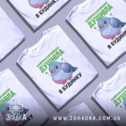 Футболка найприскіпливіша душніла білого кольору, зображена з фронтального ракурсу на манекені, фон світло-сірий, принт з малюнком пташки в пастельних тонах та текстом зеленого кольору.