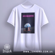 Футболка нам є куди дивитись. Біла футболка, підвішена на вішалці, з принтом, що зображує двох людей на лавці під величезною землею на фоні зірок. Текст на принті виділяється яскравим кольором.