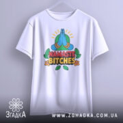 Футболка намасте бічес, біла, зображена з фронтального ракурсу на вішалці, фон світло-сірий, принт з зображенням складених рук у позі намасте, кольорові деталі з зеленим фоном та написом 'NAMASTE BITCHES' у червоному та чорному кольорах.