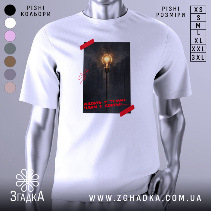 Футболка Навіть у темні часи є світло, біла футболка на манекені, фон світло-сірий, принт з зображенням лампи на фоні міста в темряві, червона стрічка на принті.