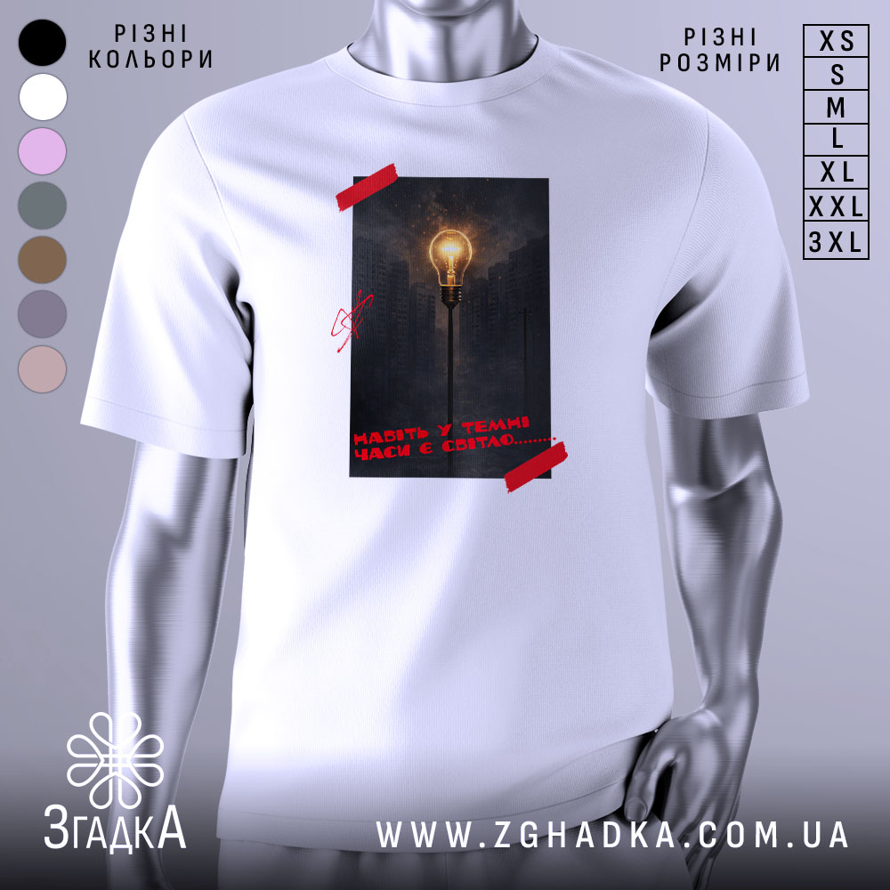 Futbolka Navit U Temni Chasy Ie Svitlo 1 Футболка Навіть у темні часи є світло, біла футболка на манекені, фон світло-сірий, принт з зображенням лампи на фоні міста в темряві, червона стрічка на принті.