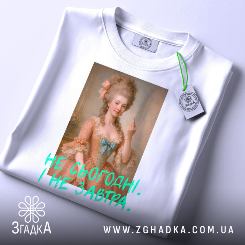 Футболка не сьогодні не завтра. Біла футболка, складена на поверхні, з принтом жінки в історичному вбранні, що показує середній палець. Текст на футболці яскравий, зелений, розташований під зображенням.