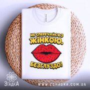 Футболка не сперечайся з жінкою. Білий колір, зображена в складеному вигляді на плетеній основі, фон білий, принт з червоними губами та жовтим текстом.