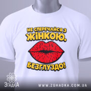 Футболка не сперечайся з жінкою. Білий колір, зображена в складеному вигляді, фон світло-сірий, принт з червоними губами та жовтим текстом, на ярлику зелена стрічка.