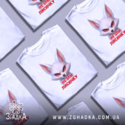 Футболка не зли лисичку. Біла футболка з принтом лисички, що має червоні очі та вираз обличчя, що викликає емоції. Футболка зображена на манекені з блискучого матеріалу, фон світлий, з легким градієнтом.