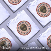 Футболка необмежено придатний, білого кольору, зображена з фронтального ракурсу на манекені, фон світло-сірий, принт у центрі з зображенням шолома та написом.