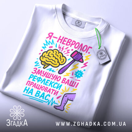 Футболка невролог білого кольору, складена на столі, фон світлий, принт яскравий, з малюнком мозку, молотка та ноги, текст кольоровий, з елементами графіки, на футболці є бірка.