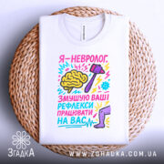 Футболка невролог білого кольору, складена на плетеній кошику, фон світлий, принт яскравий, з малюнком мозку, молотка та ноги, текст кольоровий, з елементами графіки.