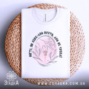 Футболка нігті як секс, складена футболка на плетеній кошику, зображення зверху, фон світлий, принт з руками та флакончиком, текст чорного кольору.