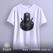 Футболка ніндзя український дух, біла, підвішена на вішалці, фон світло-сірий, принт з ніндзя в чорному капелюсі з гербом України та ланцюгами на шиї.