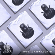 Футболка ніндзя український дух, біла, зображена на манекені, фон світло-сірий, принт з ніндзя в чорному капелюсі з гербом України та ланцюгами на шиї.