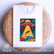 Футболка НЛО викрадення людини, біла, зображена зверху на плетеній основі, фон світлий, принт з НЛО, що світить на людину, яскраві кольори та деталі.