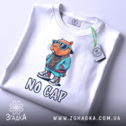 Футболка no cap капібара, біла, зображена з верхнього ракурсу, на фоні світло-сірого градієнту, принт з капібара в сонцезахисних окулярах та спортивному одязі, напис 'NO CAP' під малюнком, на футболці є етикетка з зеленим шнурком.