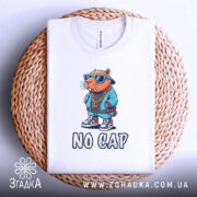 Футболка no cap капібара, біла, зображена з верхнього ракурсу, на фоні плетеного кошика, принт з капібара в сонцезахисних окулярах та спортивному одязі, напис 'NO CAP' під малюнком.