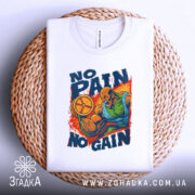 Футболка No Pain No Gain білого кольору, зображена на плетеній кошику, фон світло-сірий, принт зображає м'язистого чоловіка, який піднімає обруч, з написом 'NO PAIN NO GAIN' у яскравих кольорах, футболка складена.