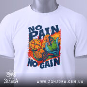 Футболка No Pain No Gain білого кольору, зображена на столі, ракурс зверху, фон світло-сірий, принт зображає м'язистого чоловіка, який піднімає обруч, з написом 'NO PAIN NO GAIN' у яскравих кольорах, на футболці є етикетка.