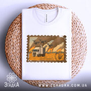 Футболка операція павутина, складена футболка білого кольору на плетеній основі, фон світлий, принт з зображенням вантажівки на фоні пожежі та дронів.