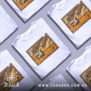 Футболка операція павутина, біла футболка на манекені, фон сірий, принт з зображенням вантажівки на фоні пожежі та дронів.