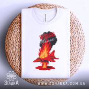 Футболка Палаючий літак, біла, зображена зверху на плетеній кошику, на фоні світлого градієнту. Принт з червоним літаком, що летить через полум'я, з текстом на чорному фоні.