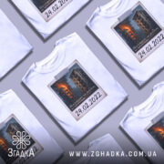 Футболка памʼять 24 лютого, біла, зображена на манекені, фон нейтральний, принт з палаючими будинками та написом "24.02.2022".