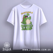 Футболка панікозавр білого кольору, підвішена на вішалці, фон світло-сірий, принт з веселим динозавром та написом 'Сьогодні я панікозавр' у зелених тонах.