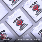 Футболка пекло переповнене, біла футболка на манекені, з кольоровим принтом, що містить текст "ПЕКЛО ПЕРЕПОВНЕНЕ, Я ПОВЕРНУЛАСЬ" та червоний тризуб на фоні хмар.