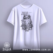 Футболка perfect hero арт білого кольору, підвішена на вішалці, з фронтального ракурсу. Принт містить малюнок персонажа з великими очима та текстом 'PERFECT HERO', на фоні світлого градієнта.