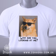 Футболка пес білого кольору, зображена на столі, ракурс зверху, фон світло-сірий, принт з собакою в окулярах та текстом "Why are you looking at me?", на футболці є етикетка.