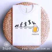Футболка п’ятниця еволюція, біла, складена на плетеній кошику, фон світло-сірий, принт з еволюцією людини, текст 'FRIDAY!!!' під малюнком.