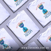 Футболка подорож диким лісом — кілька складених футболок, композиція на столі.