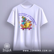 Футболка поїхала кукуха. Біла футболка, підвішена на вішалці, з принтом качок на скейтборді. Принт кольоровий, з текстом українською мовою. Фон світло-сірий, що підкреслює яскравість дизайну.
