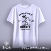 Футболка Полювання на Демогоргона білого кольору, підвішена на вішалці, фон світло-сірий, принт чорного кольору з демогоргоном, текстом 'NORTH TEN TWO HOURS' та 'HUNTER HAWKINS HEROES'.