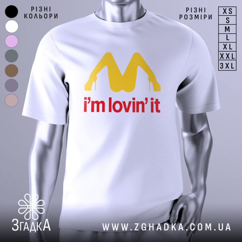 Футболка поп арт іронія, біла, зображена на манекені з правого боку, фон світло-сірий, принт жовтого кольору у формі літери М з червоним написом 'i'm lovin' it'.