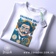 Футболка портрет Сальвадора Далі, біла, зображена в складеному вигляді, фон світло-сірий, принт з портретом Далі, прикрашений метеликами та годинниками, на комірці є етикетка.