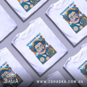 Футболка портрет Сальвадора Далі, біла, зображена з фронтального ракурсу на манекені, фон світло-сірий, принт з портретом Далі в яскравих кольорах, з годинниками та метеликами.