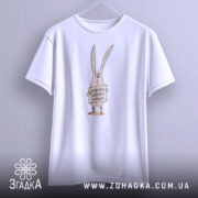 Футболка поверніть доброту, біла, підвішена на вішалці, фон світло-сірий, принт з малюнком кролика, що тримає табличку з написом 'Поверніть доброту в моду!'.