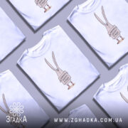 Футболка поверніть доброту, біла, зображена на манекені, фон світло-сірий, принт з малюнком кролика, що тримає табличку з написом 'Поверніть доброту в моду!'.