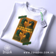 Футболка працюю сутками, біла, розкладена на поверхні, фон світлий, принт з чотирма качками в окулярах, текст "ПРАЦЮЮ СУТКАМИ" на жовтому фоні, з етикеткою.