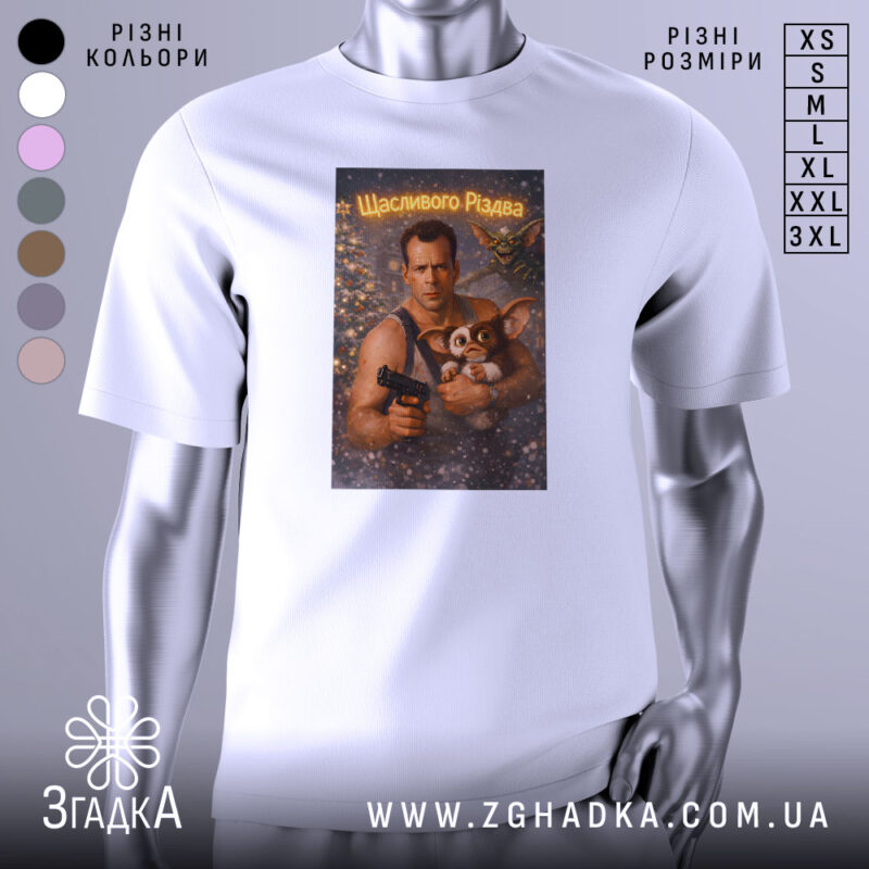 Футболка різдвяний бойовик, біла, зображена на манекені, фон нейтральний, принт зображує чоловіка з пістолетом та істотою з великими вухами, текст на принті говорить 'Щасливого Різдва'.
