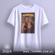 Футболка різдвяний бойовик, біла, підвішена на вішалці, фон світлий, принт зображує чоловіка з пістолетом та істотою, текст на принті 'Щасливого Різдва'.