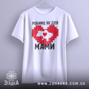 Футболка робимо як для мами, біла, підвішена на вішалці, фон світло-сірий, принт червоного кольору у формі серця з контуром України, напис чорним шрифтом.
