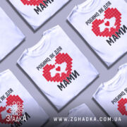 Футболка робимо як для мами, біла, зображена з фронтального ракурсу на манекені, фон світло-сірий, принт червоного кольору у формі серця з контуром України та написом чорним шрифтом.