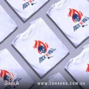 Футболка Rock N Roll білого кольору, зображена з фронтального ракурсу на манекені, фон світло-сірий, принт з червоним полум'ям та черепом з синіми деталями, текст 'ROCK'N'ROLL' виконаний у темно-синьому кольорі.