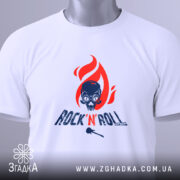 Футболка Rock N Roll білого кольору, зображена з верхнього ракурсу, на ній видно етикетку з зеленим шнурком, фон світло-сірий, принт з червоним полум'ям та черепом, текст 'ROCK'N'ROLL' у темно-синьому кольорі.