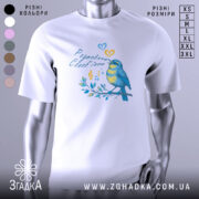 Футболка розмовляю солов’їною білого кольору, зображена на манекені з блискучою поверхнею, фон світло-сірий, принт з пташкою, що співає, в жовто-блакитних тонах, оточена нотами та листям.