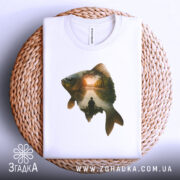 Футболка рибак на заході, складена біла футболка на плетеній основі, принт з рибою та рибалкою на фоні заходу сонця.