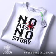 Футболка ризик історія, біла, лежить на поверхні, зображена зверху, фон світло-сірий, принт чорного кольору з червоним акцентом у вигляді плями, на комірці є етикетка.