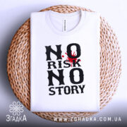 Футболка ризик історія, біла, лежить на плетеній кошику, фон світло-сірий, принт чорного кольору з червоним акцентом у вигляді плями.
