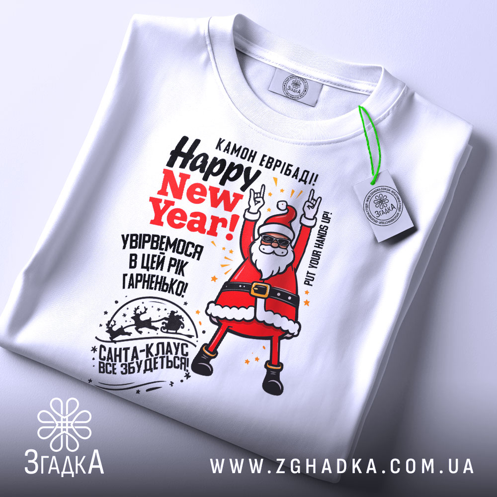 Футболка Санта новорічний вайб, біла, складена на столі, фон світло-сірий, принт з Сантою в червоному костюмі, текст 'Happy New Year!' у червоному кольорі, з етикеткою на рукаві.