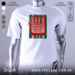 Футболка сардини білого кольору, зображена на манекені, з принтом у вигляді консервної банки з сардинами, червоний текст на зеленому фоні, фон світло-сірий.